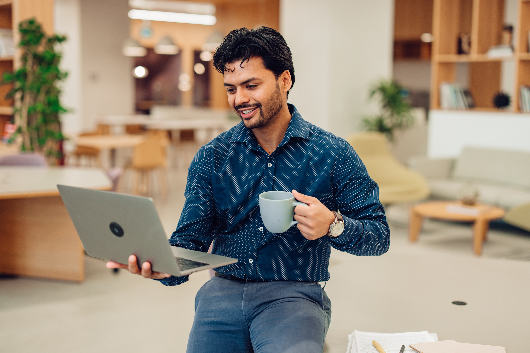 A man looking at a laptop while drinking a cup of coffee