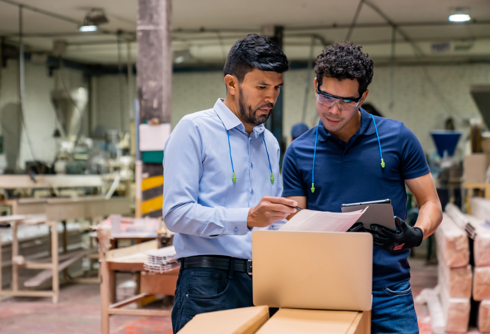 Two men inspecting paperwork in a factory