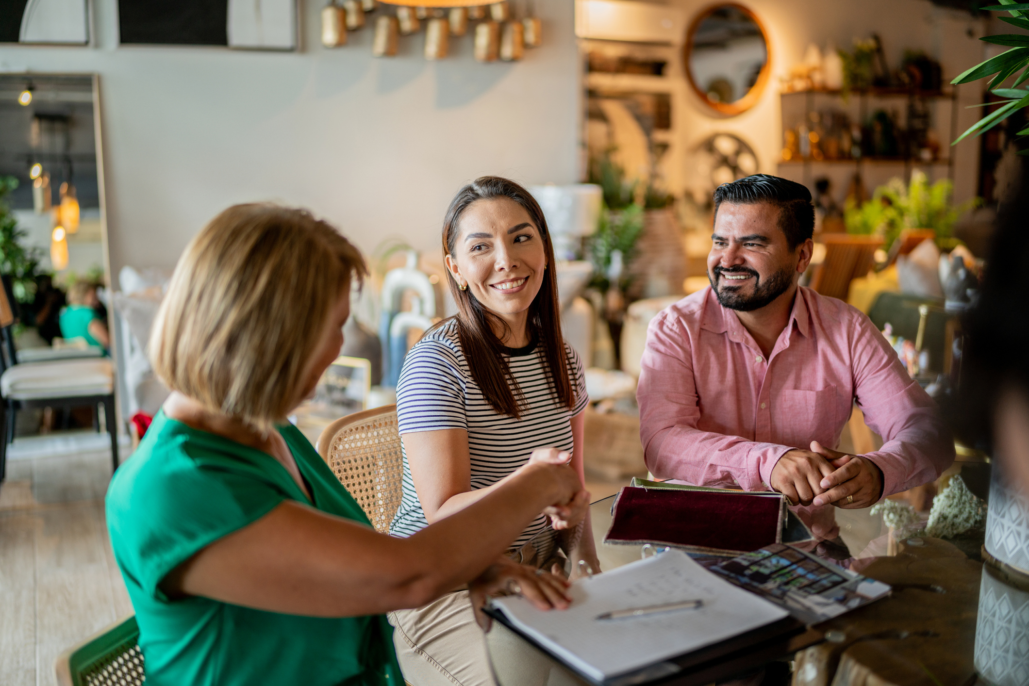 Three people meeting at a coffee shop and shaking hands over a business deal