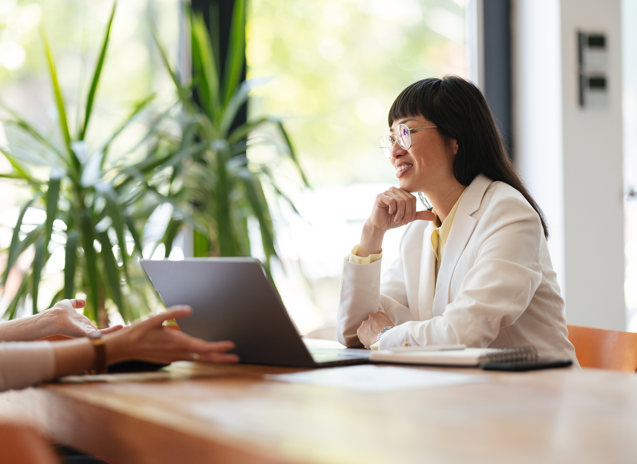 A young women in front of a laptop talking with a colleague