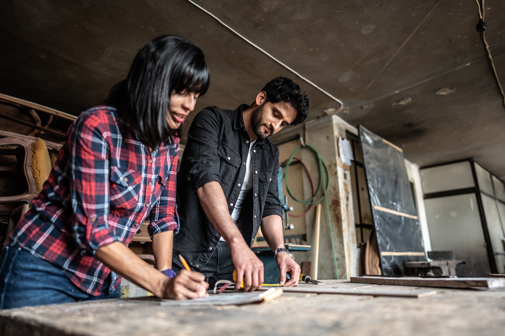 Two people drawing up plans in a woodshop