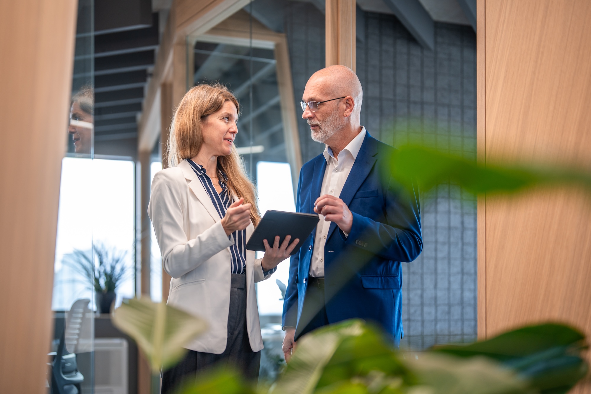 People in a office are having a conversation while looking at a tablet