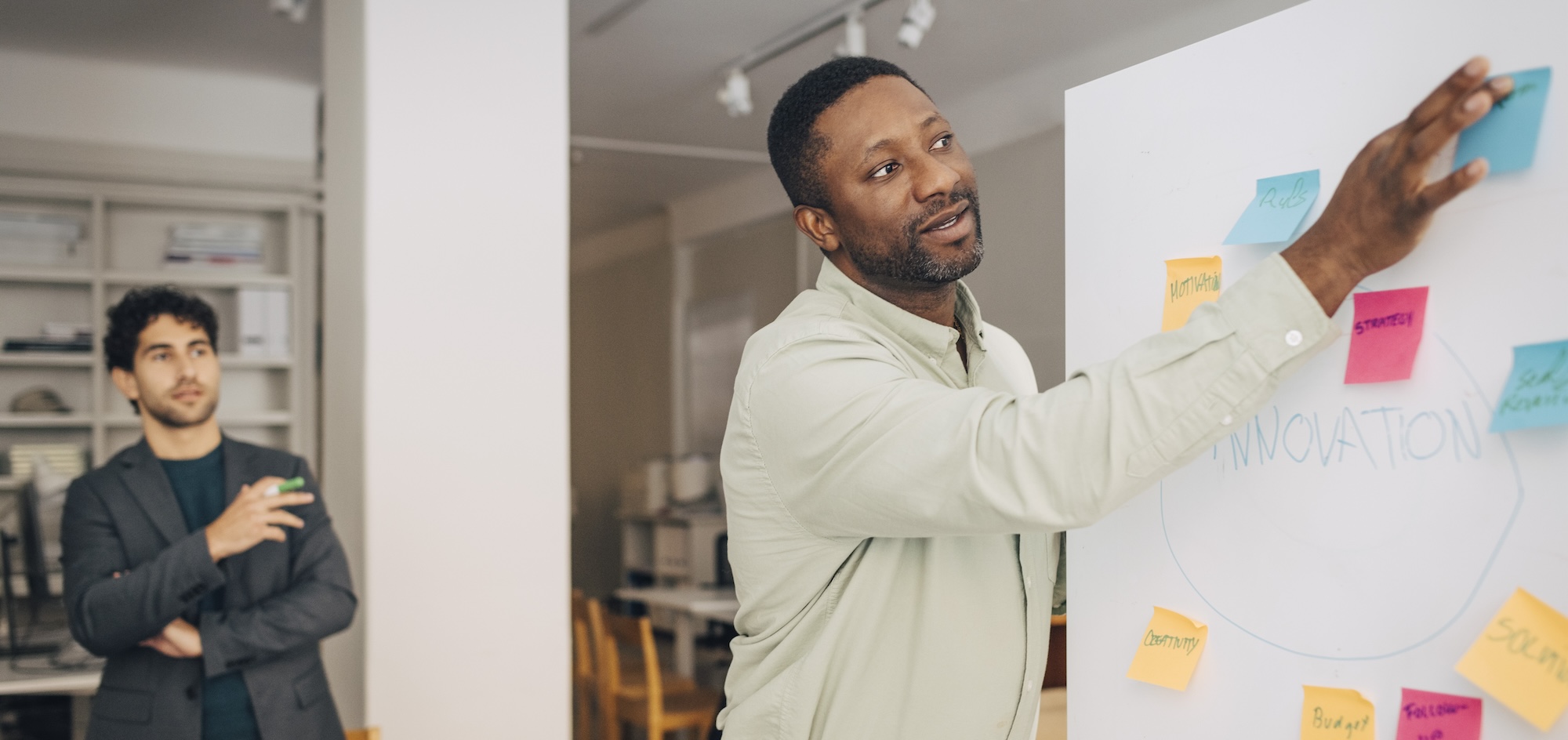 A man is discussing strategies while looking at a whiteboard