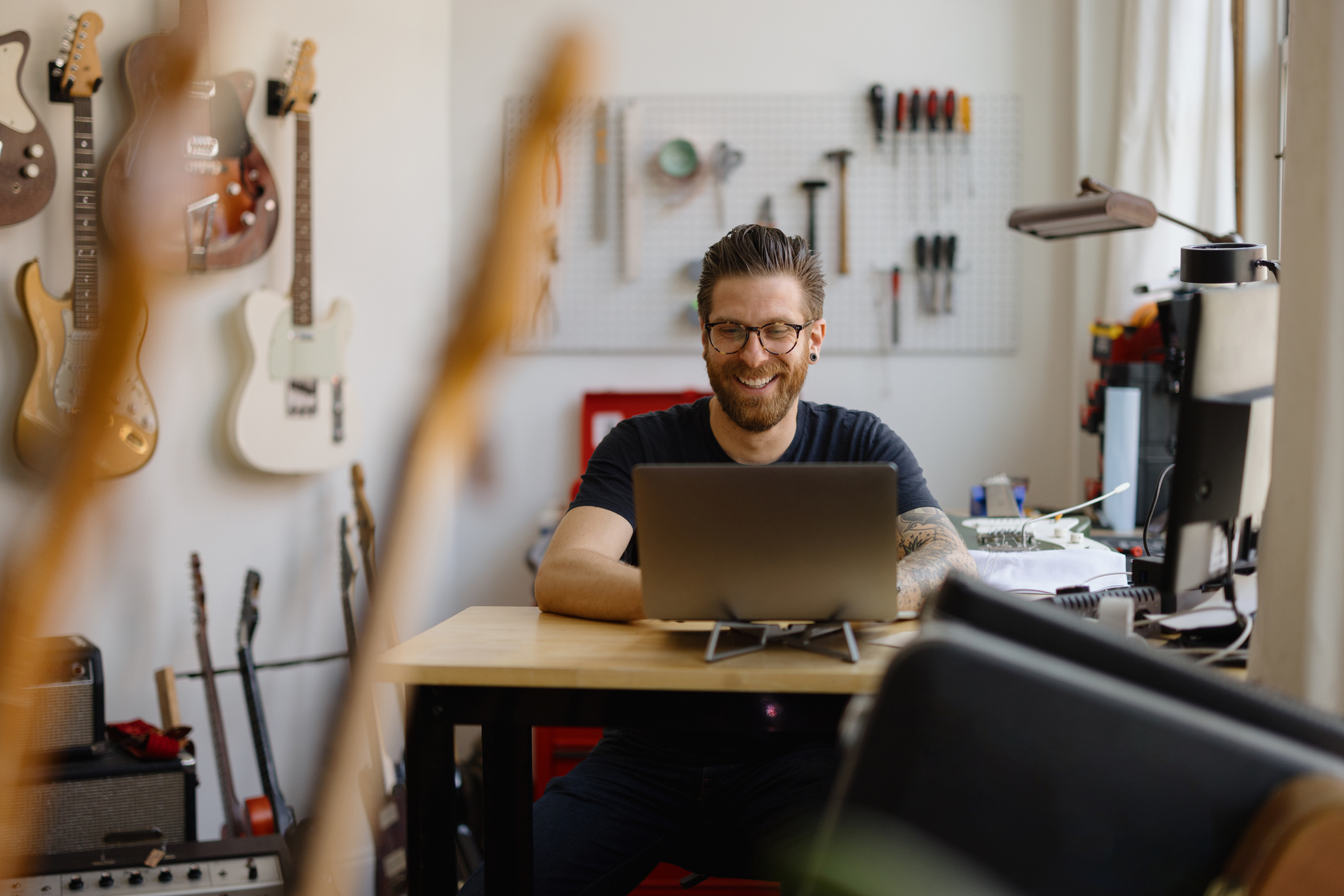 A man working on a laptop in a guitar workshop