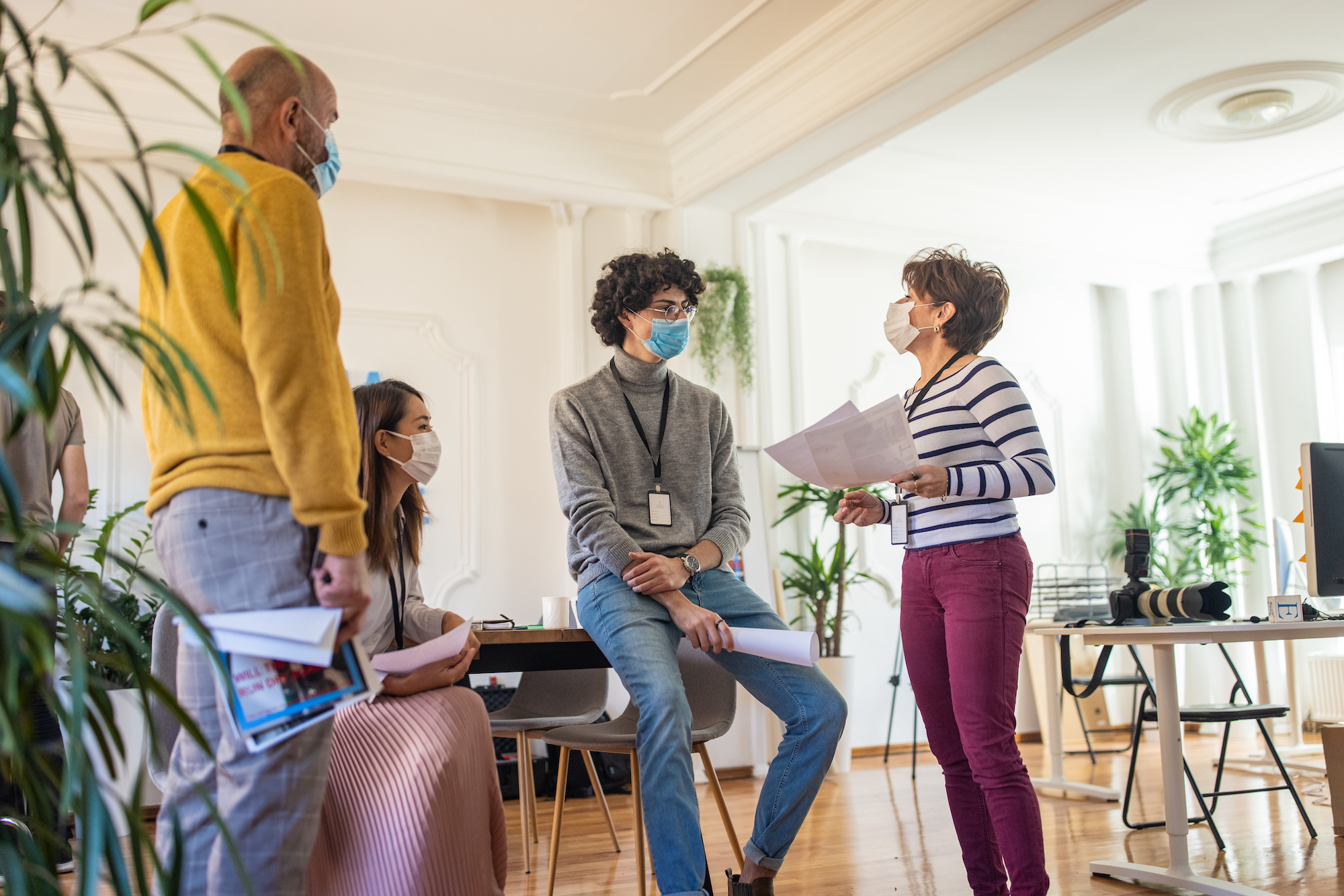 A group of office workers wearing masks and talking about a project.